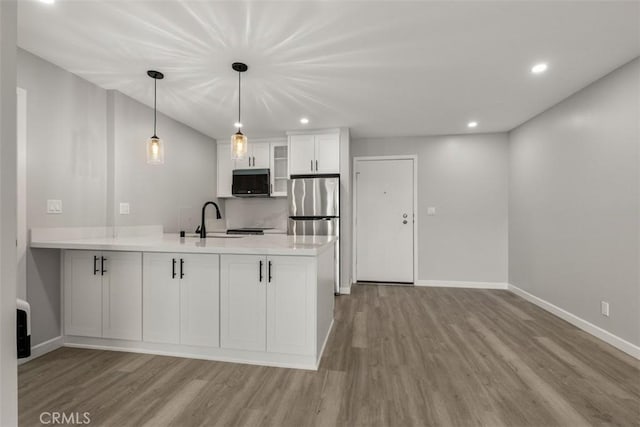 kitchen with a peninsula, stainless steel appliances, wood finished floors, and a sink
