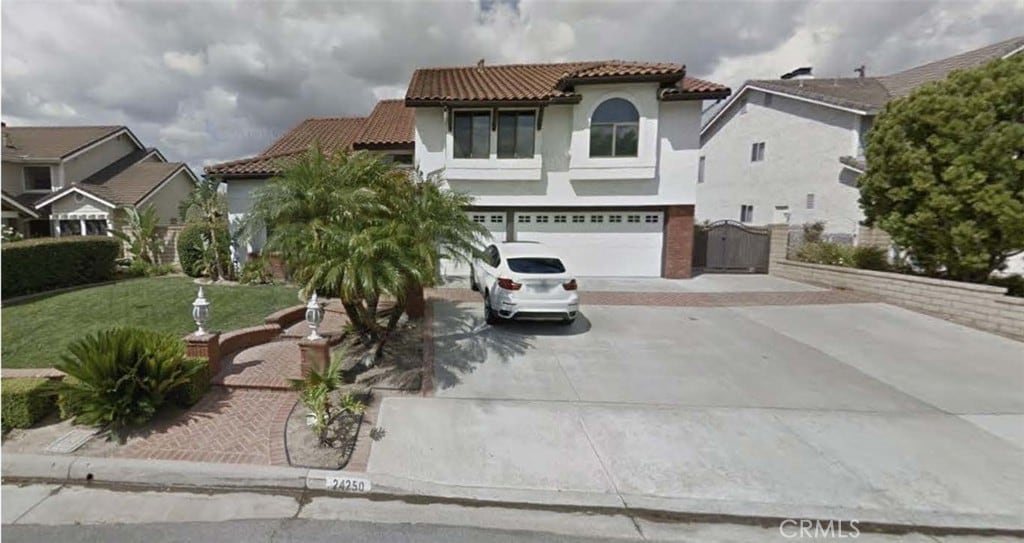 mediterranean / spanish-style home featuring a gate, an attached garage, a tile roof, concrete driveway, and stucco siding