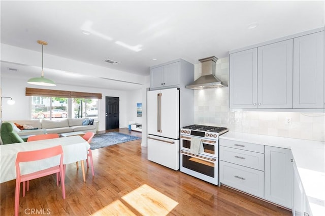 6023 Acacia Ave, Whittier, CA 90601 - kitchen with premium appliances, wall chimney range hood, light wood-style flooring, open floor plan, and light countertops