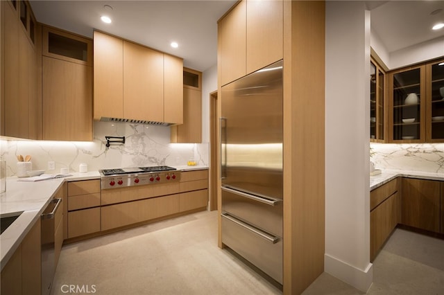 kitchen with backsplash, light stone counters, stainless steel appliances, and glass insert cabinets