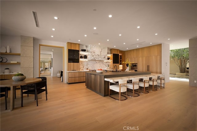 kitchen featuring open shelves, light wood-type flooring, modern cabinets, and a kitchen breakfast bar
