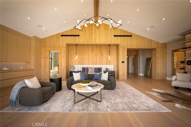 living area with a notable chandelier, wood walls, high vaulted ceiling, and wood finished floors
