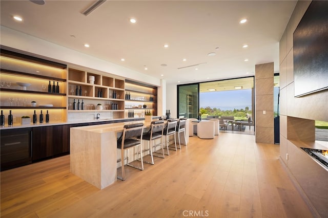 bar featuring a wall of windows, light wood-style flooring, recessed lighting, and bar