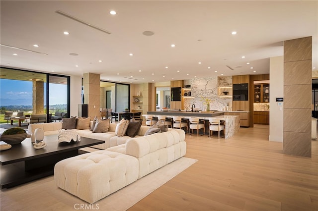 living area featuring a wall of windows, light wood-style flooring, and recessed lighting