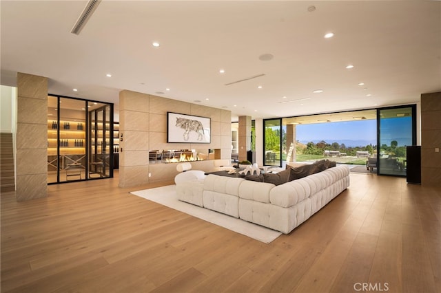 living room featuring recessed lighting, light wood finished floors, visible vents, and floor to ceiling windows