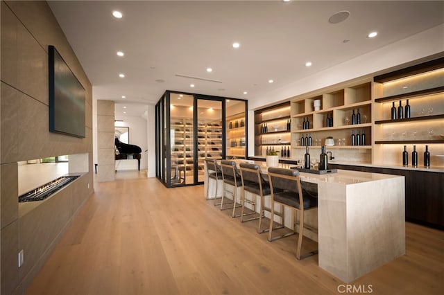 bar featuring light wood finished floors, wet bar, and recessed lighting