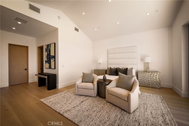 bedroom featuring visible vents, wood finished floors, baseboards, and high vaulted ceiling