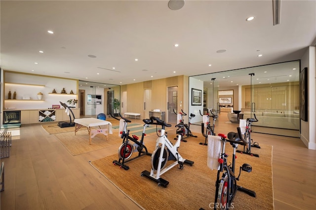 workout area with light wood-style floors and recessed lighting