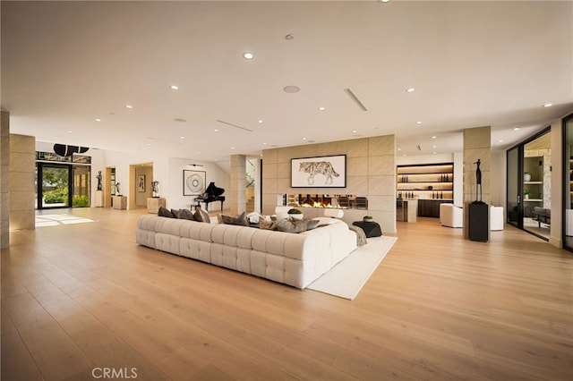 living room with recessed lighting, ornate columns, and light wood-style floors