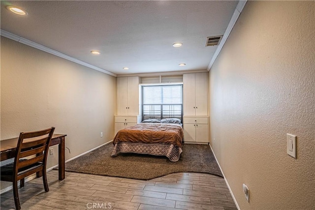bedroom featuring baseboards, light wood-style floors, visible vents, and crown molding