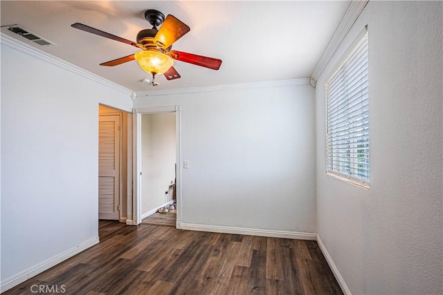 spare room featuring baseboards, ornamental molding, visible vents, and dark wood-style floors