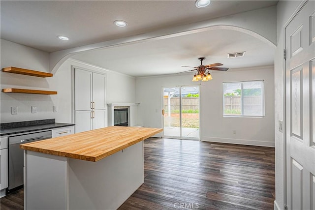kitchen with dishwasher, butcher block counters, visible vents, open shelves, and arched walkways