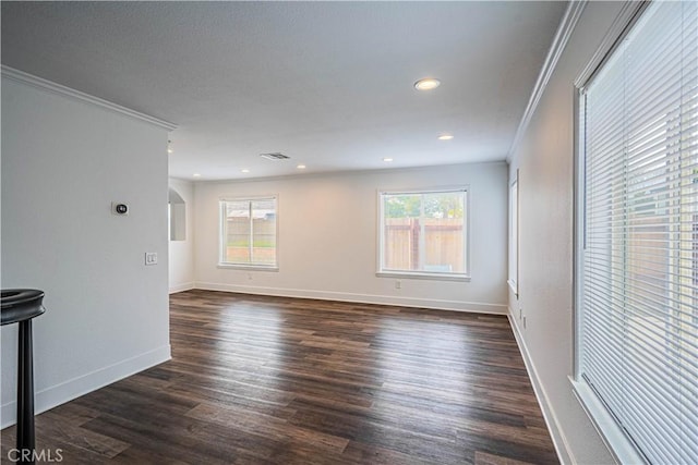 empty room featuring dark wood-style flooring, ornamental molding, arched walkways, and baseboards