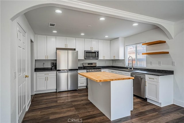 kitchen with a sink, visible vents, arched walkways, wooden counters, and appliances with stainless steel finishes