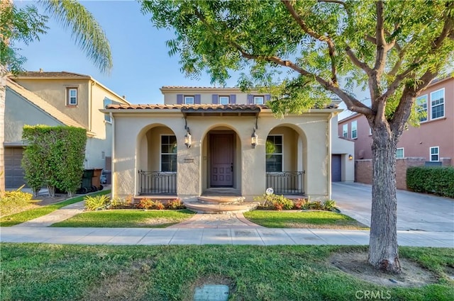 mediterranean / spanish-style house with covered porch, driveway, a tile roof, a garage, and stucco siding