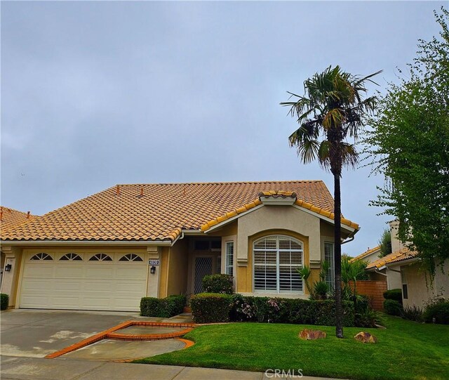4839 W Forest Oaks Ave, Banning, CA 92220 - mediterranean / spanish-style home featuring concrete driveway, an attached garage, stucco siding, a front lawn, and a tile roof