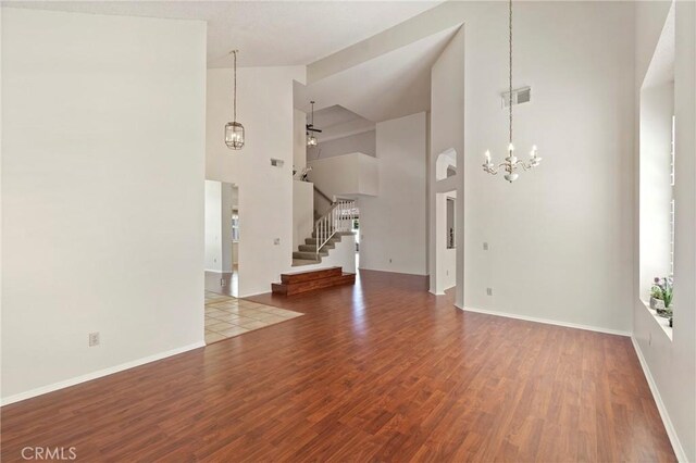 4839 W Forest Oaks Ave, Banning, CA 92220 - unfurnished living room featuring a chandelier, high vaulted ceiling, stairs, wood finished floors, and baseboards