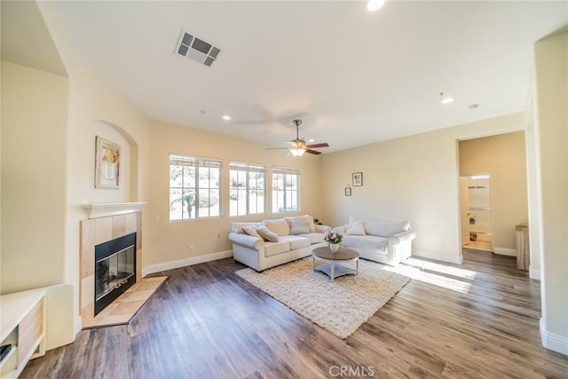 living room with a ceiling fan, baseboards, visible vents, wood finished floors, and a fireplace