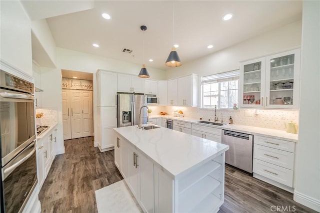 kitchen featuring a sink, stainless steel appliances, backsplash, and a kitchen island with sink