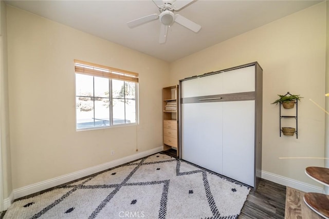 unfurnished bedroom featuring wood finished floors, baseboards, and ceiling fan