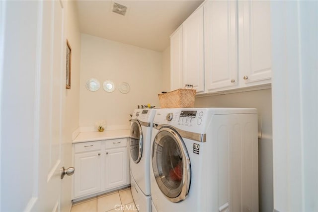 laundry room with cabinet space, visible vents, light tile patterned flooring, and washer and clothes dryer