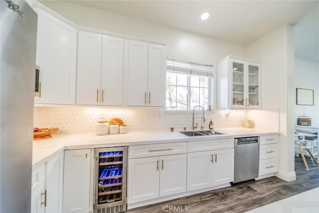 kitchen with stainless steel dishwasher, beverage cooler, a sink, white cabinetry, and dark wood-style floors