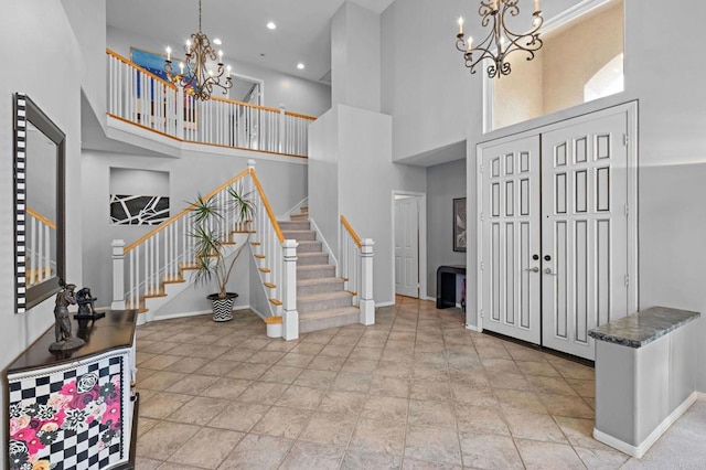 foyer with a chandelier, baseboards, a high ceiling, and stairs