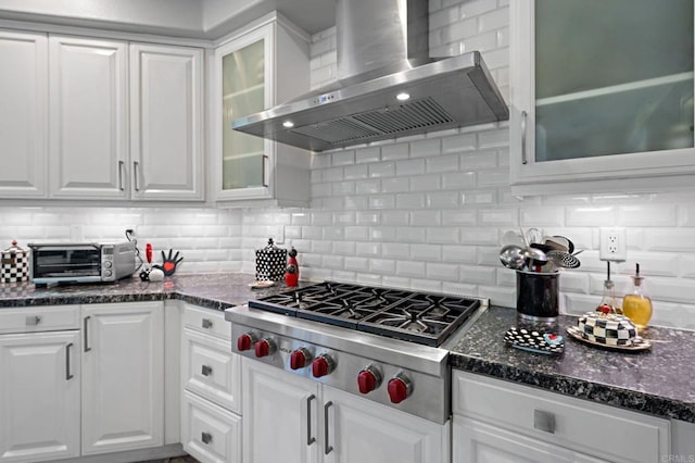 kitchen with wall chimney exhaust hood, a toaster, white cabinetry, backsplash, and stainless steel gas stovetop