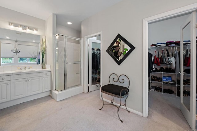 bathroom with an inviting chandelier, a stall shower, baseboards, vanity, and a spacious closet