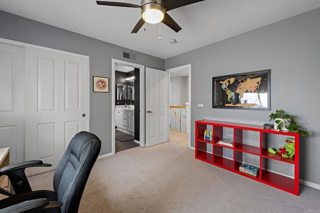 carpeted office space featuring baseboards, ceiling fan, and visible vents
