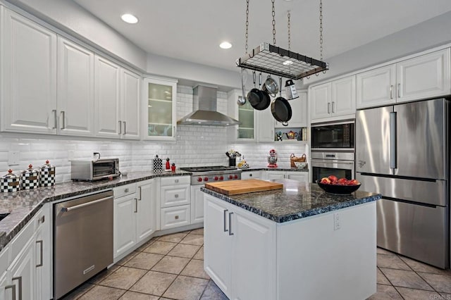 kitchen with stainless steel appliances, light tile patterned flooring, wall chimney exhaust hood, decorative backsplash, and white cabinets