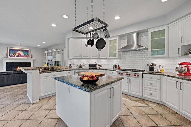 5054 Seachase Way, San Diego, CA 92130 - kitchen with wall chimney exhaust hood, light tile patterned floors, a kitchen island, a lit fireplace, and recessed lighting