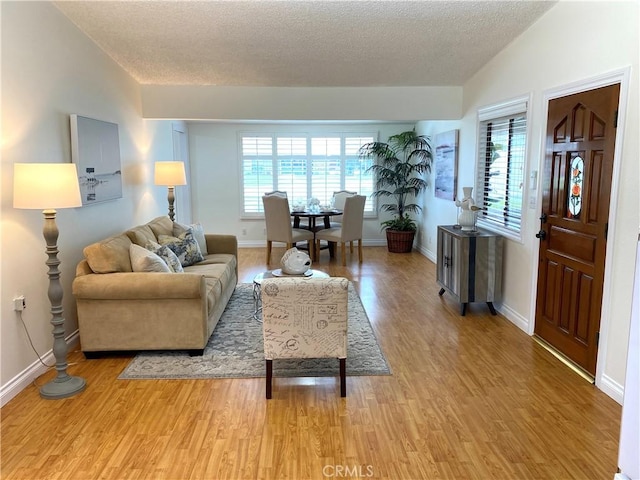 living room with baseboards, light wood-type flooring, and a textured ceiling