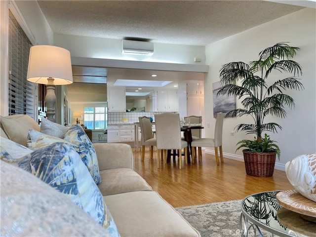 13310 Fairfield Ln Unit M7-176B, Seal Beach, CA 90740 - living area featuring a wall mounted air conditioner, light wood-style floors, a textured ceiling, and baseboards