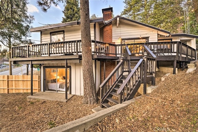 rear view of property with a chimney, stairway, a wooden deck, and fence