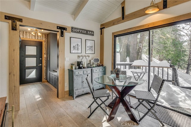 dining room featuring plenty of natural light, a barn door, and lofted ceiling with beams