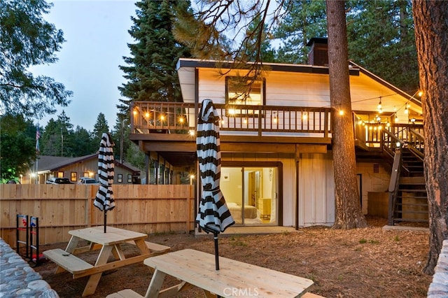 rear view of house featuring a chimney, stairs, a deck, and fence