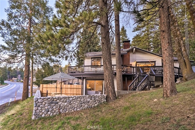 back of house featuring fence, stairway, a chimney, and a wooden deck