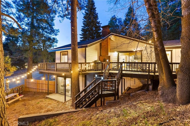 back of house with fence, a chimney, a wooden deck, and stairs