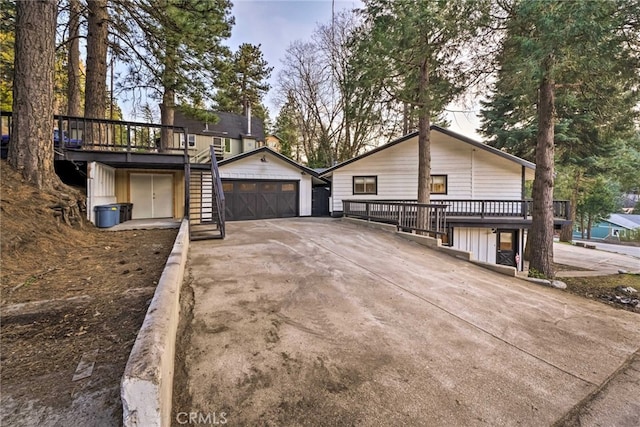 exterior space featuring stairway, a wooden deck, an outbuilding, and driveway