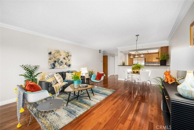 living area featuring wood finished floors, ornamental molding, baseboards, and a textured ceiling