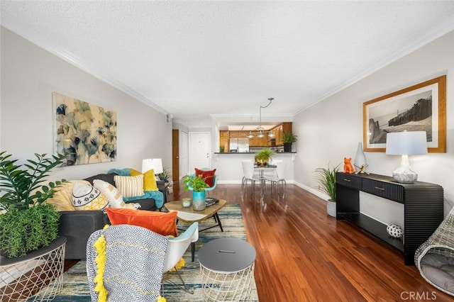 living area featuring wood finished floors, ornamental molding, baseboards, and a textured ceiling