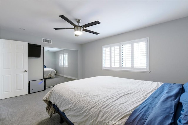 carpeted bedroom featuring a closet, visible vents, baseboards, and ceiling fan