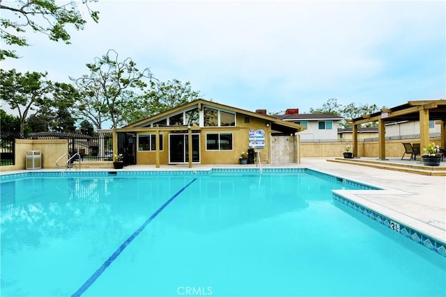 community pool with a patio area and fence