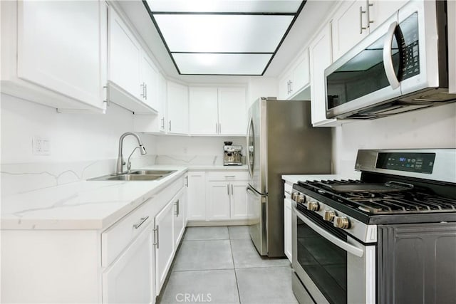 kitchen featuring a sink, light tile patterned flooring, white cabinetry, light stone countertops, and appliances with stainless steel finishes