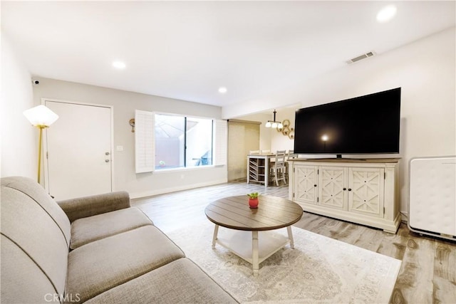 living room featuring light wood-type flooring, visible vents, recessed lighting, an inviting chandelier, and baseboards