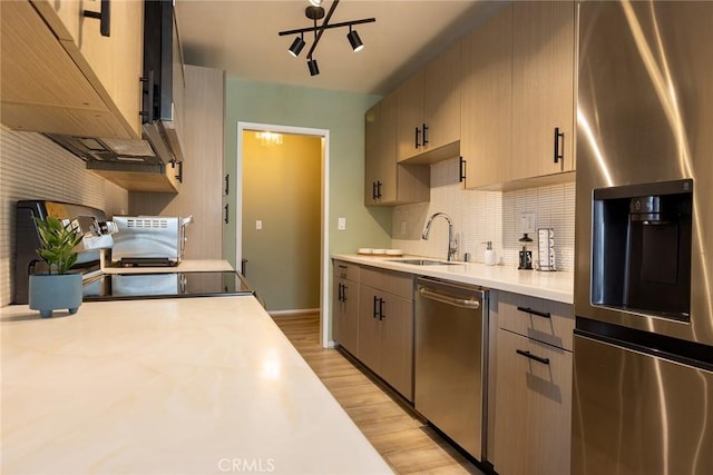 5875 Doverwood Dr Unit 309, Culver City, CA 90230 - kitchen featuring appliances with stainless steel finishes, a sink, light countertops, light wood-style flooring, and decorative backsplash