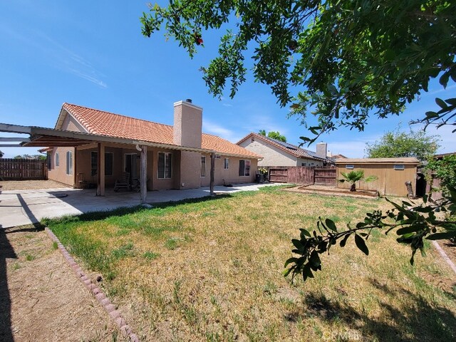 628 Vintner St, Los Banos, CA 93635 - rear view of property with a tiled roof, a chimney, fence, a yard, and a patio area