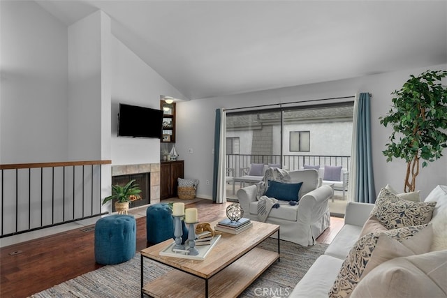 living room featuring lofted ceiling, a tiled fireplace, and wood finished floors