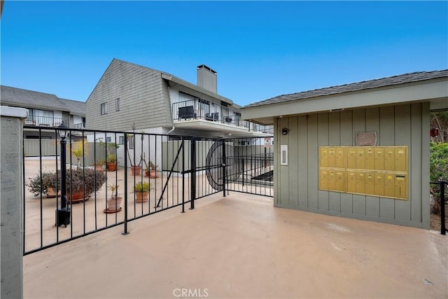 view of patio / terrace featuring a balcony, fence, and mail area